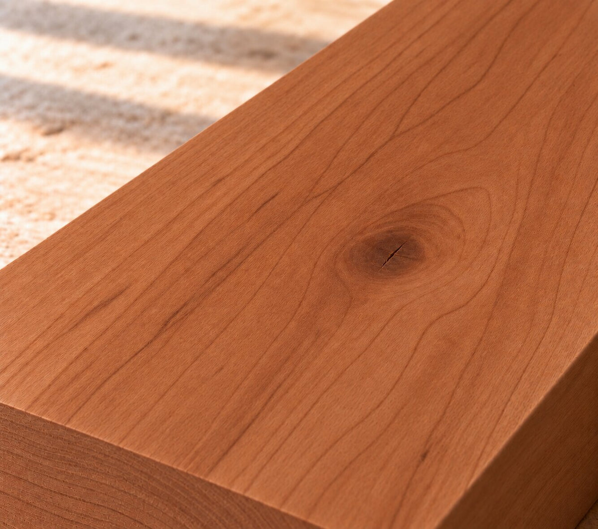 Close-up of solid American cherry board showing fine grain, rich reddish-brown colour and a natural knot