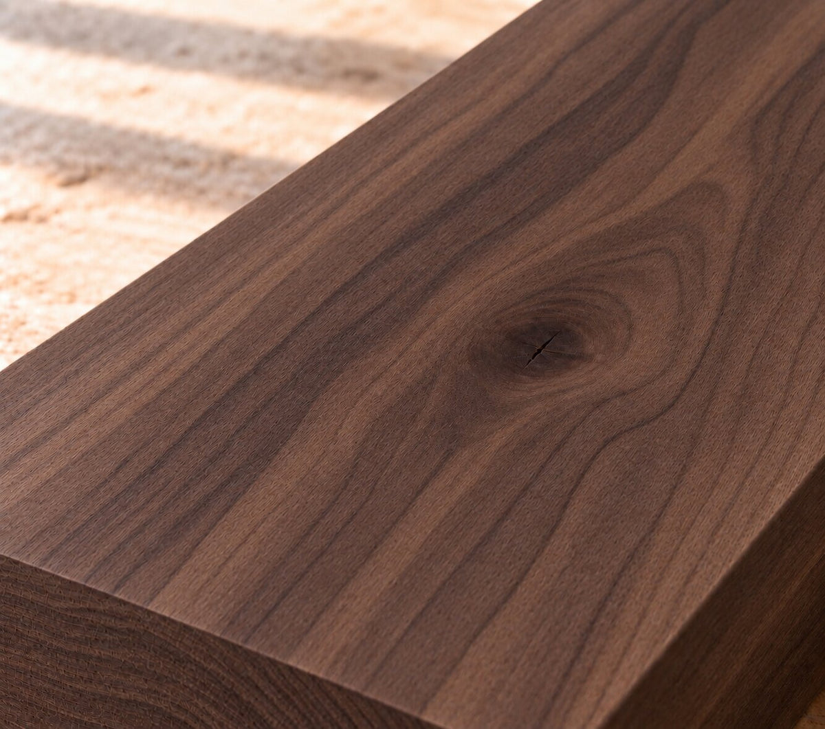 Close-up of solid American walnut board showing rich dark grain and a natural knot