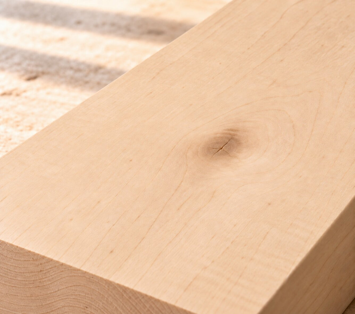 Close-up of solid maple board showing fine grain and a natural knot